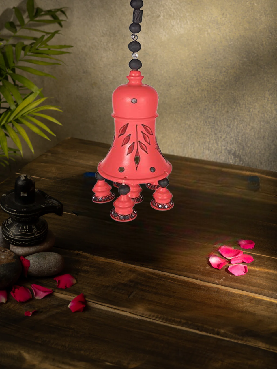 Handcrafted terracotta hanging bell with floral design, perfect for home decor, displayed with rose petals and sunflower background.
