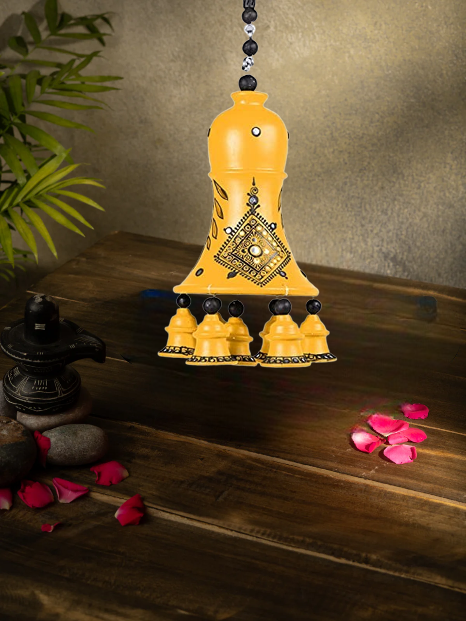 Handcrafted terracotta hanging bell with floral design, perfect for home decor, displayed with rose petals and sunflower background.