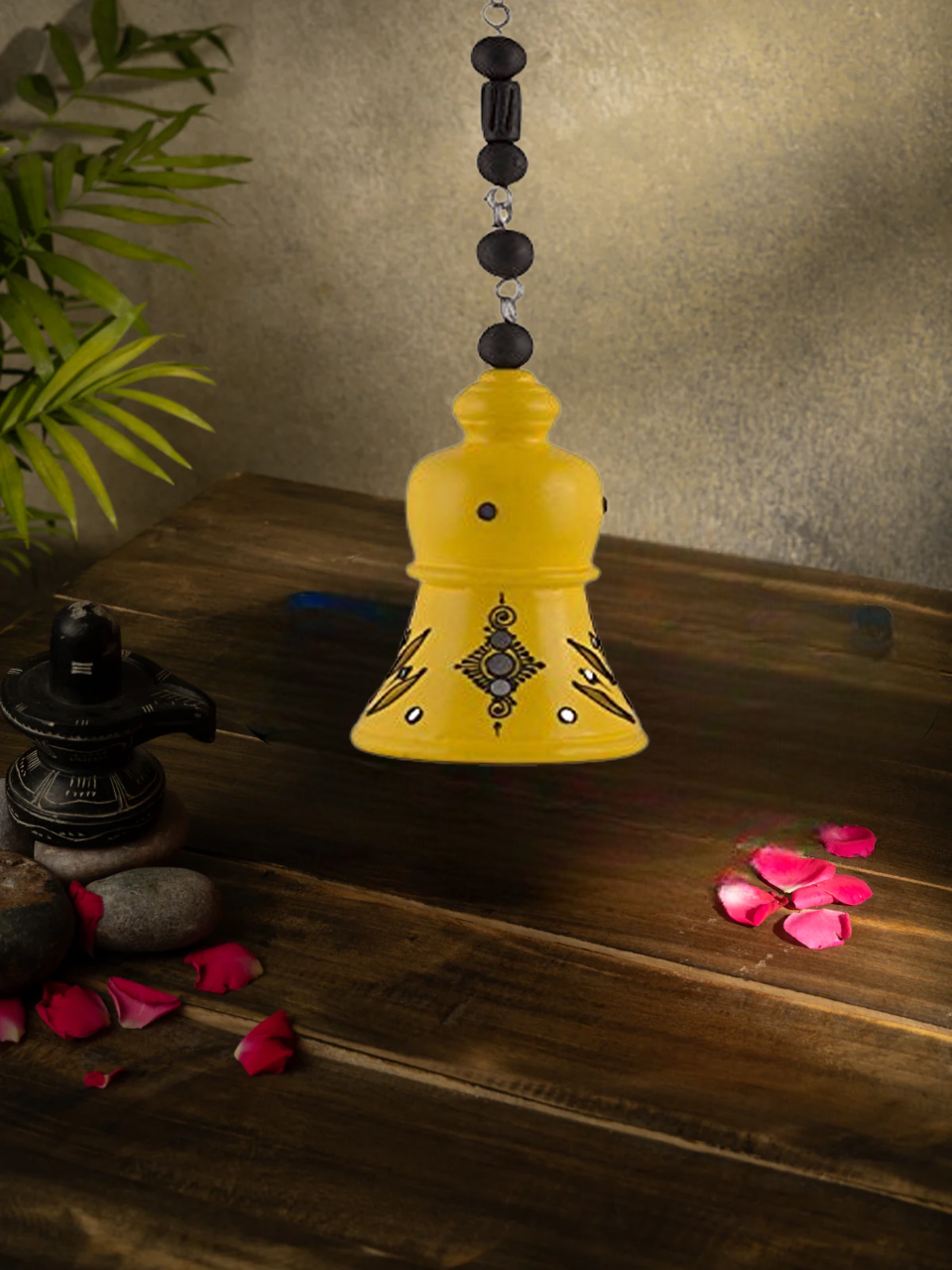 Handcrafted terracotta hanging bell with floral design, perfect for home decor, displayed with rose petals and sunflower background.