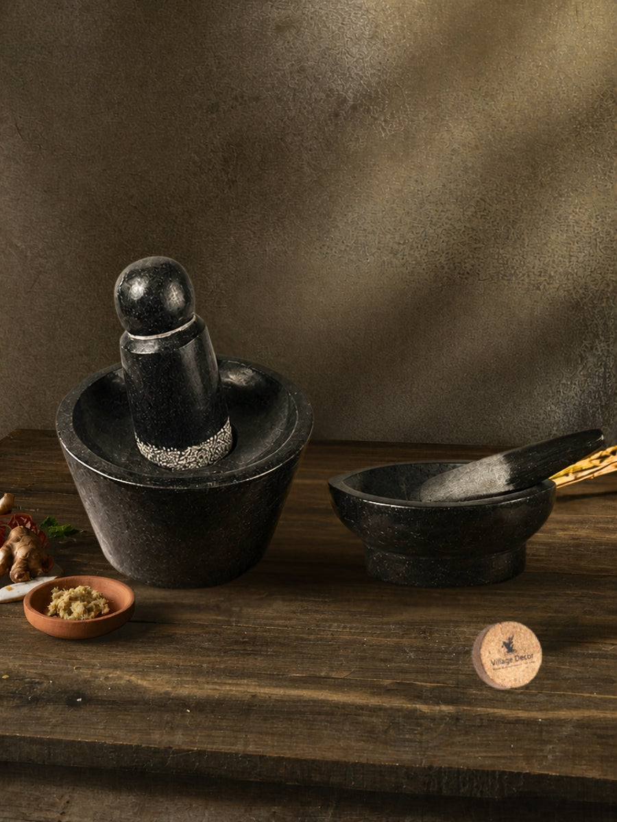 Handmade Rubu rollu (Attukal) and Klavam (Kharal) stone kitchen tools placed on a rustic wooden surface with lentils and garlic for traditional cooking.