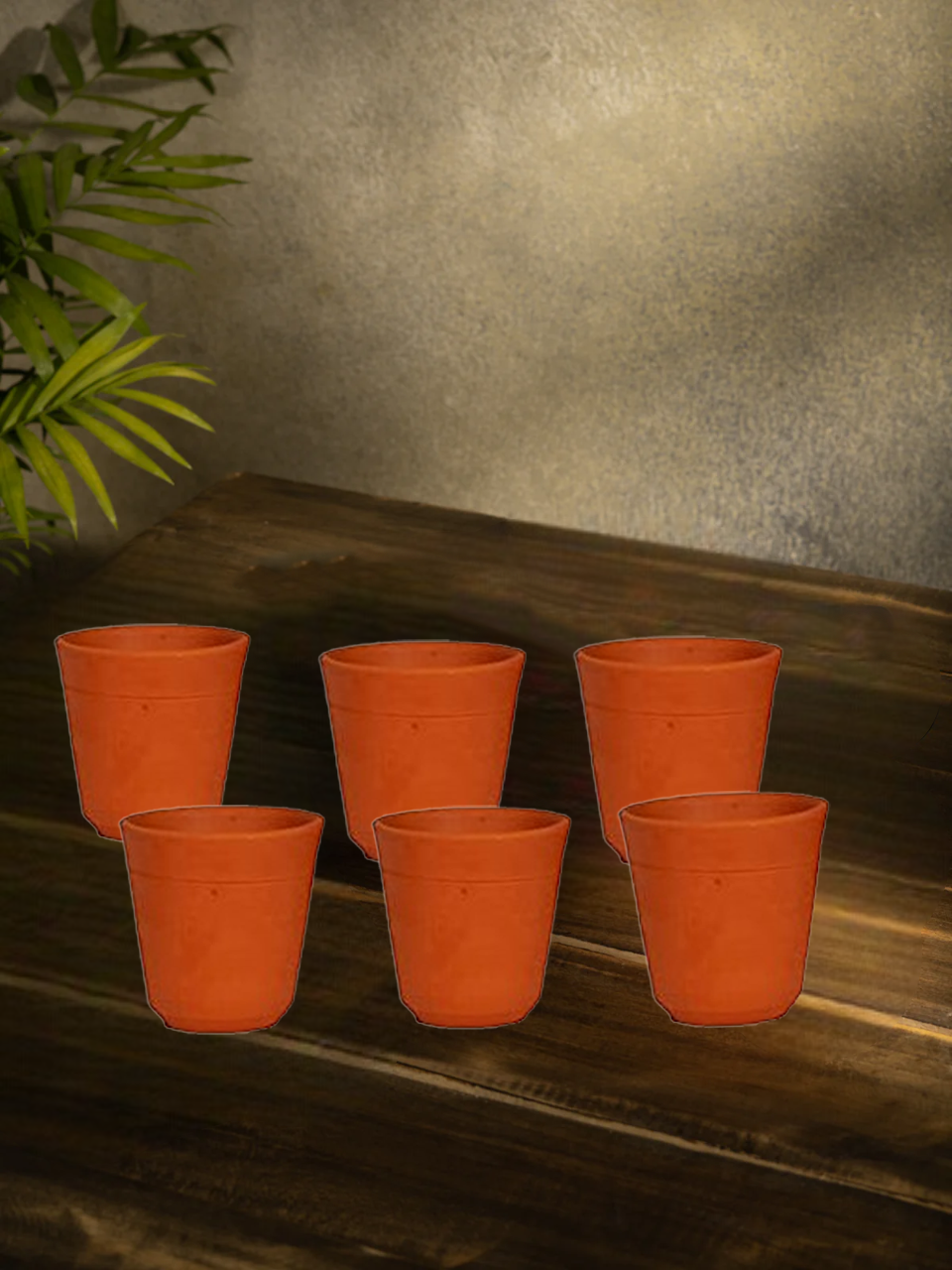 Set of six eco-friendly terracotta drinking glasses displayed in a vibrant lifestyle background with fruits and herbs, ideal for natural and healthy drinking.