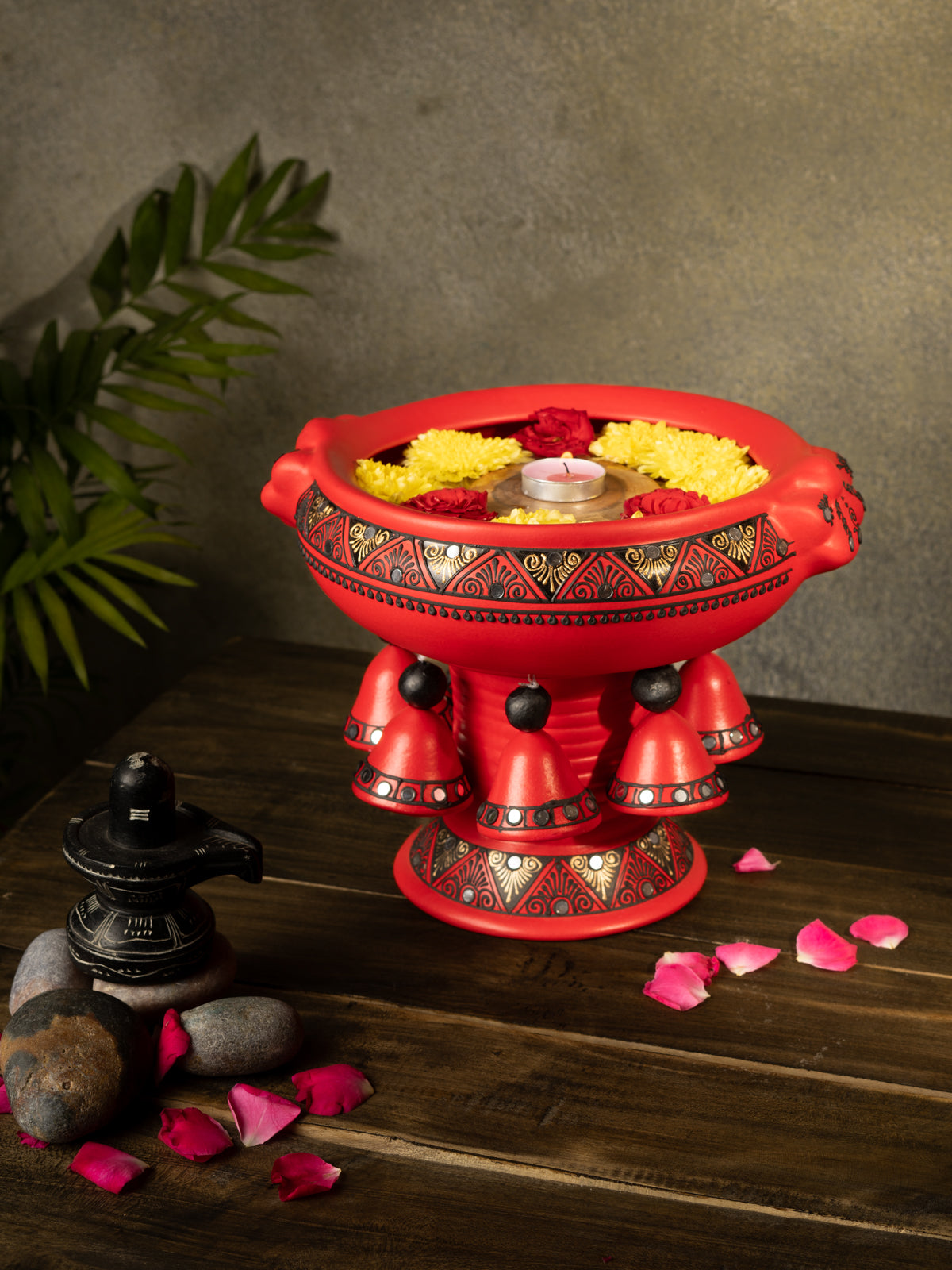 Handcrafted multicolor terracotta urli with floral design placed on a wooden surface, styled with rose petals and traditional decor for a festive look.