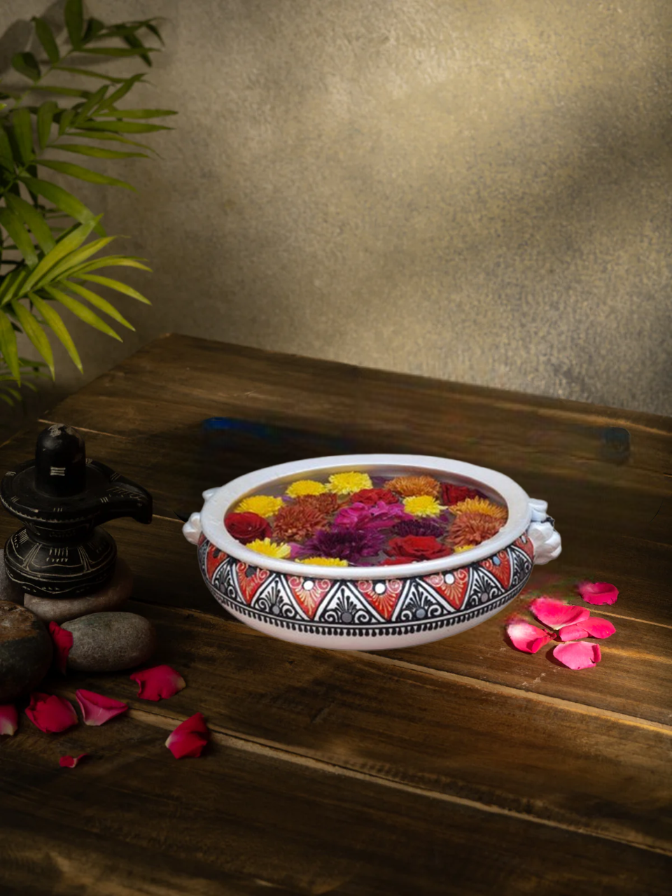 Handcrafted White terracotta urli with Handpainted design, styled with rose petals and traditional decor for a festive look.