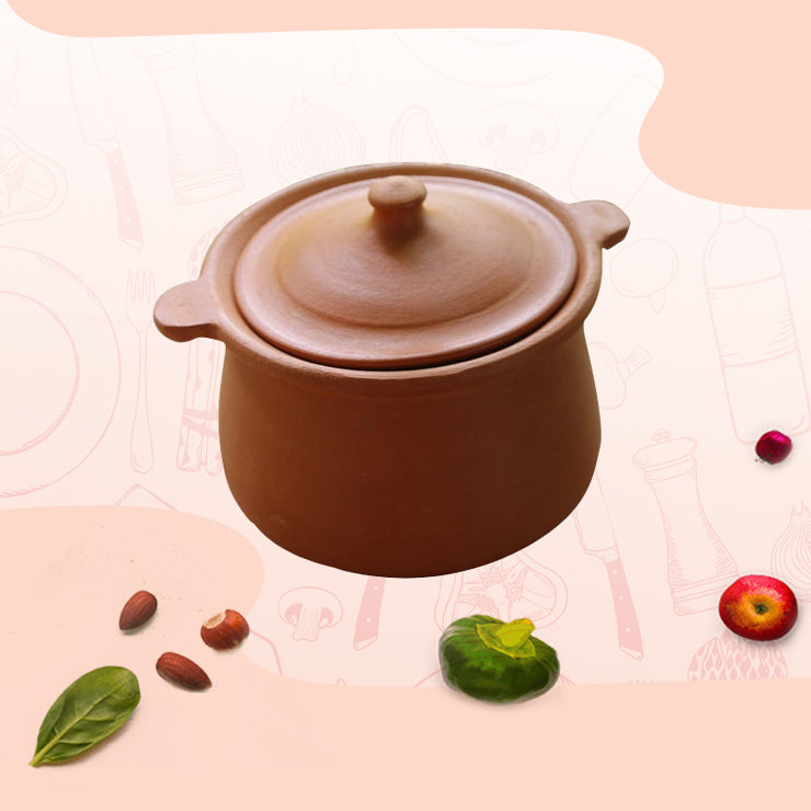 Traditional earthen clay cooking pot with lid surrounded by fresh ingredients like spinach, tomato, and nuts.