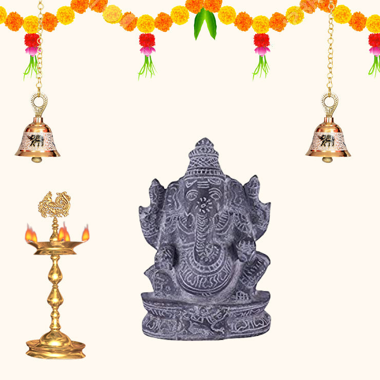 Black stone Ganesha idol with traditional pooja setup, festive home decoration with diya, bells and marigold flowers.