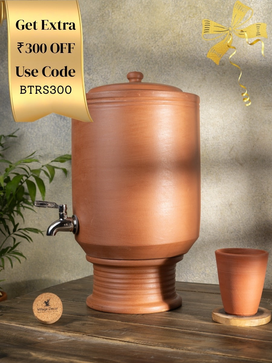 Terracotta water dispenser with a small glass  on a wooden surface