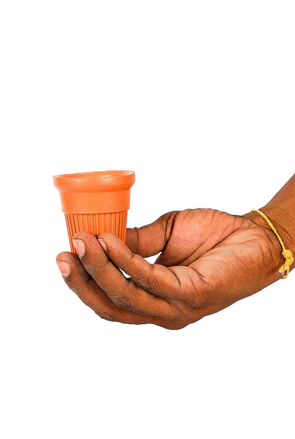 Terracotta disposable chai tea cup held in hand, showcasing its compact size and traditional ribbed clay design.

