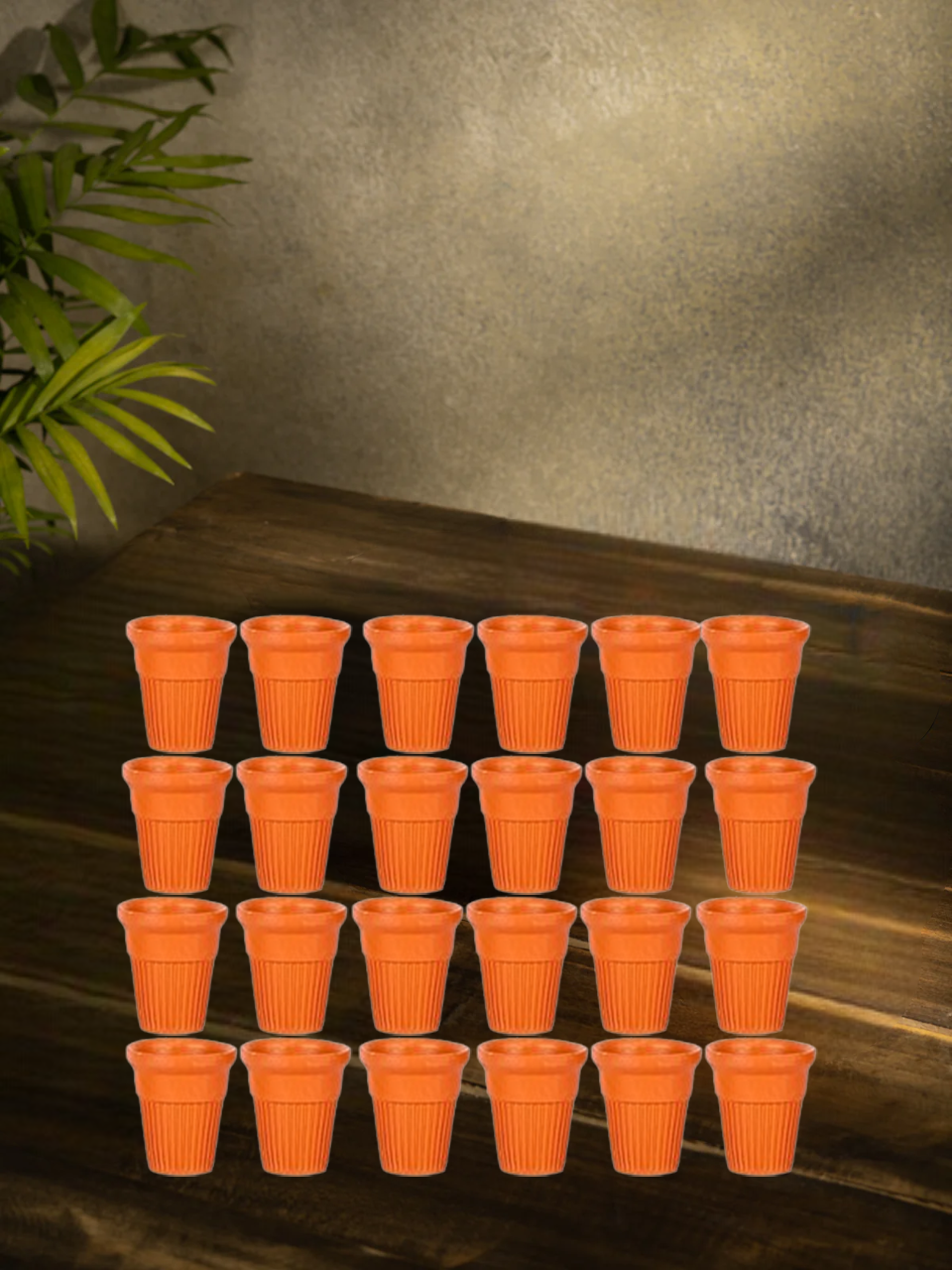 Pack of 24 disposable terracotta chai cups arranged on a rustic wooden table with a traditional background setting, ideal for eco-friendly tea serving.