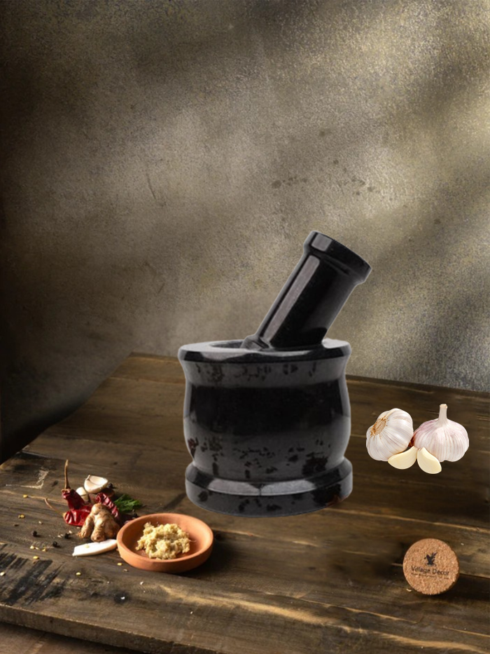 Mortar and pestle also called as ginger garlic crusher on a wooden surface with garlic and herbs, against a textured wall.