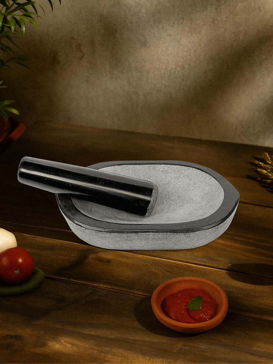 Granite boat-shaped Kharal Nanni Kalvam styled in a traditional kitchen setting, featuring a lightweight stone design and comfortable pestle for grinding spices and ingredients during everyday cooking.
