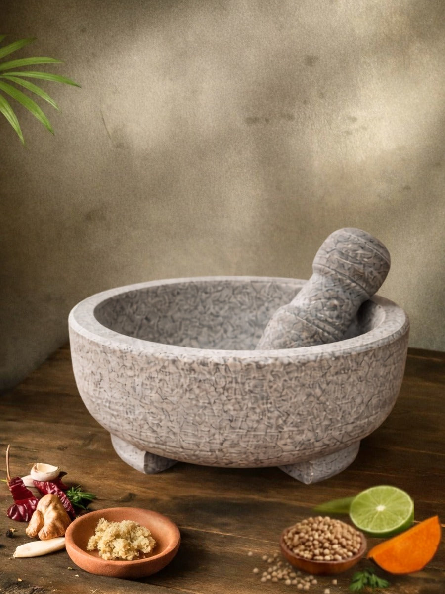 Unpolished mortar and pestle filled with spices, placed on a wooden table with garlic, ginger, and chili around it