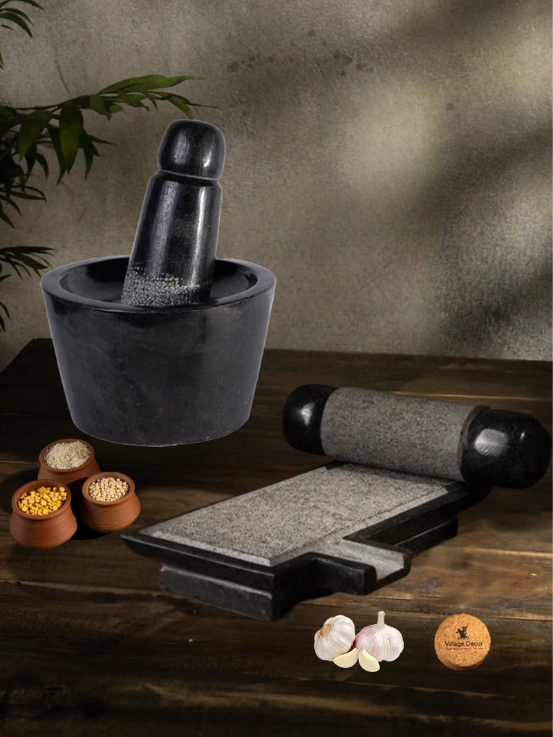 Handmade Silbatta (Ammikal) and Rubbu Rolu (Attukal) stone kitchen tools placed on a rustic wooden surface with lentils and garlic for traditional cooking.

