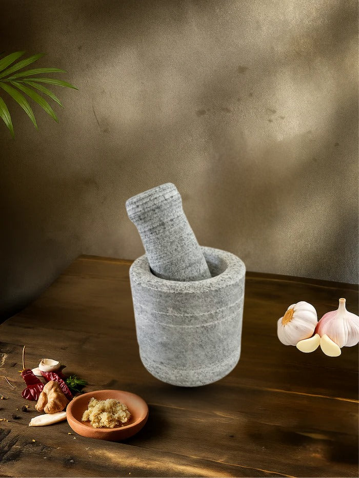 Unpolished mortar and pestle filled with spices, placed on a wooden table with garlic, ginger, and chili around it
