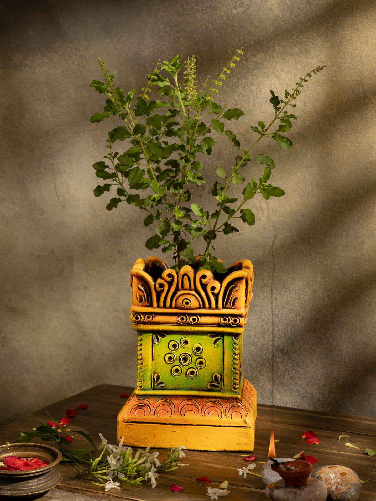 Handcrafted terracotta Tulsi Pot with Tulsi plant in traditional Vrindavan style, placed in a pooja setup with natural lighting and sacred decor.
