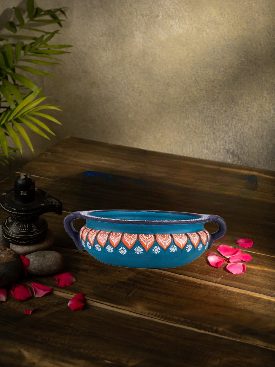 Handcrafted multicolor terracotta urli with floral design placed on a wooden surface, styled with rose petals and traditional decor for a festive look.
