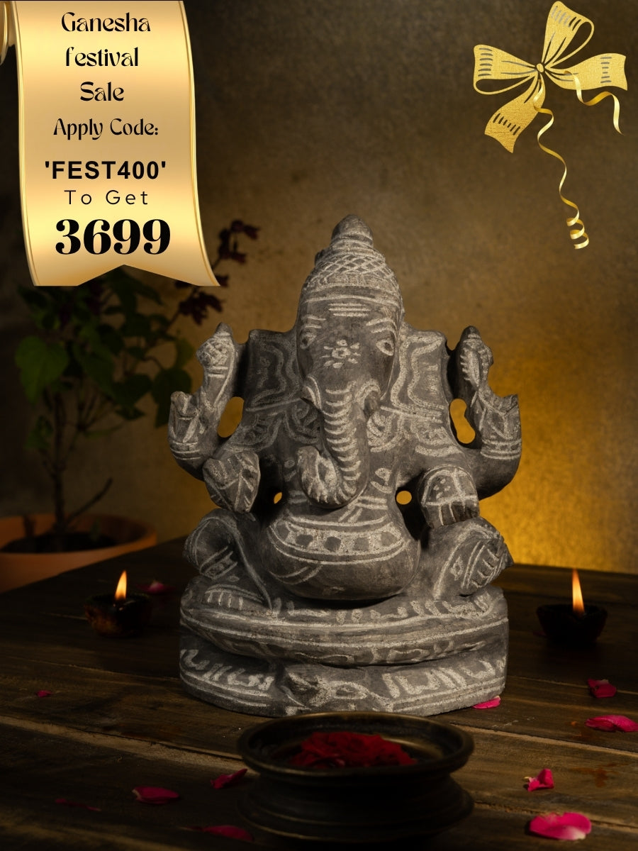 Black Stone Vinayagar Idol in Traditional Pooja Setup with Diyas, Rose Petals, and Tulsi Plant for Home Decor or Vastu Placement.
