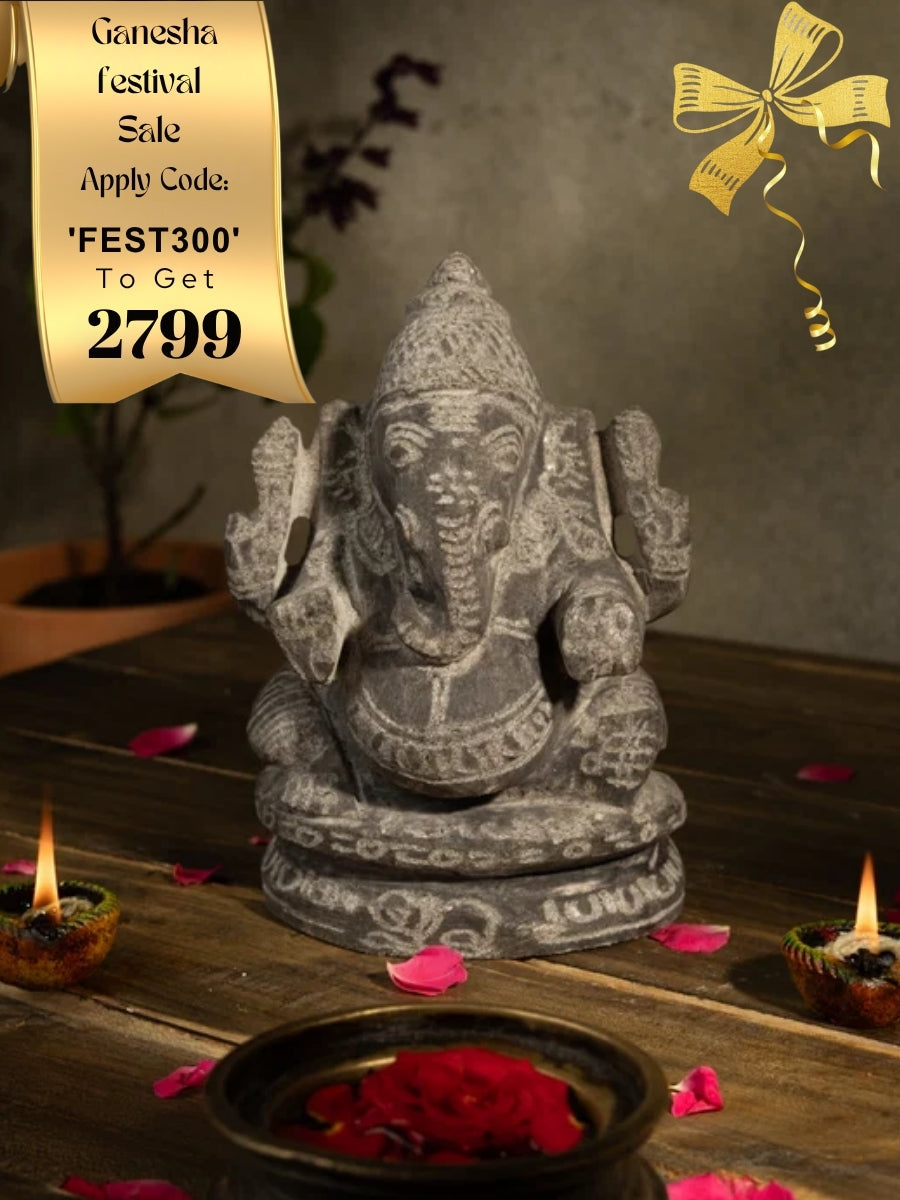 Black Stone Vinayagar Idol in Traditional Pooja Setup with Diyas, Rose Petals, and Tulsi Plant for Home Decor or Vastu Placement.
