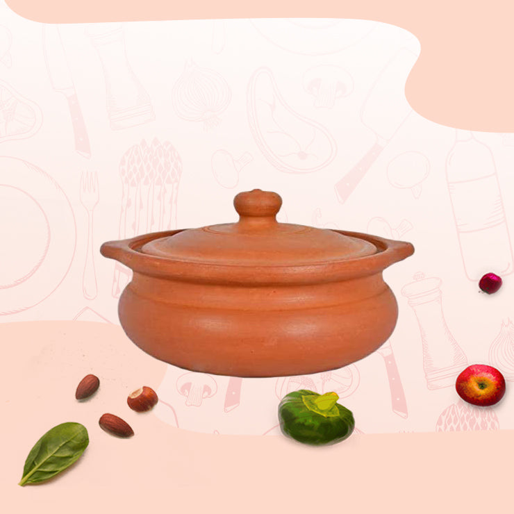 Traditional earthen clay cooking pot with lid surrounded by fresh ingredients like spinach, tomato, and nuts.


